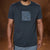 A man wearing a dark navy blue crewneck t-shirt with a square graphic print on the chest featuring a blue and black abstract pattern and the text 'BOY TOY STUDIO'.