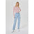 A woman modeling a red and white striped long-sleeve crop top with light-wash blue jeans and white sneakers, standing against a light gray studio background.