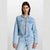 A model wearing a light-wash cropped denim jacket with matching high-waisted jeans, photographed against a plain light gray studio background.