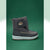 A dark gray winter boot with a padded ankle strap featuring a small hedgehog patch, set against a solid green background.