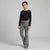 A young girl modeling a black long-sleeve crewneck top and gray flared pants against a light gray studio background.