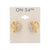 A pair of gold crescent-shaped hoop earrings with pavé crystal detailing, displayed on a beige card labeled 'ON 34TH' against a white background.