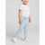 A toddler wearing light blue denim jeans with colorful embroidered flowers, a white t-shirt, and white sneakers, standing against a light gray studio background.
