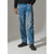 A person wearing medium-wash blue distressed jeans with faded details, a black sweater, and black shoes, standing against a light gray studio background.