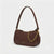A dark brown leather shoulder bag with a gold chain strap and gold hardware, shown on a clean white background. The brand name 'COACH' is visible in gold lettering on the front and on the hanging leather tag.