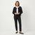 A woman modeling a black textured cropped jacket with a white collar, paired with black trousers and black flats, against a clean white studio background.