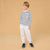 A young boy modeling a long-sleeve navy and white striped shirt, white jogger pants, and navy blue sneakers against a solid beige studio background.