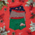 Three pairs of children's boxer briefs are arranged in a flat lay on a bright red background with holiday decorations. The top pair is navy blue with a red car print, the middle pair has red, white, and green stripes, and the bottom pair is green with a red car graphic.