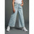 A person wearing light blue wide-leg denim jeans with an allover white heart outline pattern, paired with a white top and white sneakers, standing against a dark gray studio background.