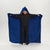 A child wearing a black hoodie and pants stands in a studio while holding open a large blue hooded blanket or wearable blanket with a shark-face hood, showing the shark teeth detail on the hood.