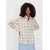 A woman with curly black hair wearing a cream-colored long-sleeve button-up plaid shirt with thin green and blue lines, paired with a light blue skirt, against a plain light gray background.
