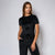 A woman modeling a black short-sleeve velvet top and matching black drawstring pants against a light gray studio background.