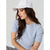 A woman wearing a light blue ribbed short-sleeve top and a white baseball cap, shown in a studio setting against a light gray background.
