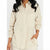 A woman wearing a light beige linen button-up shirt with a chest pocket and long sleeves, shown from the neck down against a plain white background.