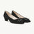 Black patent leather shoes with a block heel on a light gray background