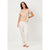 A woman modeling a two-piece pajama set consisting of a short-sleeve beige t-shirt and white pants with a small floral pattern, set against a plain light gray studio background.