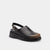 A single black leather clog sandal with a low platform sole, a backstrap with a silver buckle, and a small heart-shaped metal detail on the vamp, shown against a light gray background.