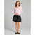A woman modeling a light pink long-sleeve V-neck sweater paired with a black pleated mini skirt and black flats, holding a black handbag against a plain gray studio background.
