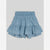 A pair of light blue denim shorts for toddlers, featuring a smocked elastic waistband and a tiered ruffle hem with a small white floral print, shown flat on a light gray background.