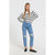 A woman modeling a black and white horizontally striped long-sleeve knit sweater paired with light-wash distressed blue jeans and black loafers, standing against a plain light gray studio background.