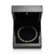 A silver tennis bracelet with rectangular clear stones, displayed inside an open black presentation box with a black velvet interior.