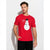 A man wearing a bright red short-sleeve t-shirt with a cartoon snowman graphic on the front, paired with black pants, standing against a light gray studio background.