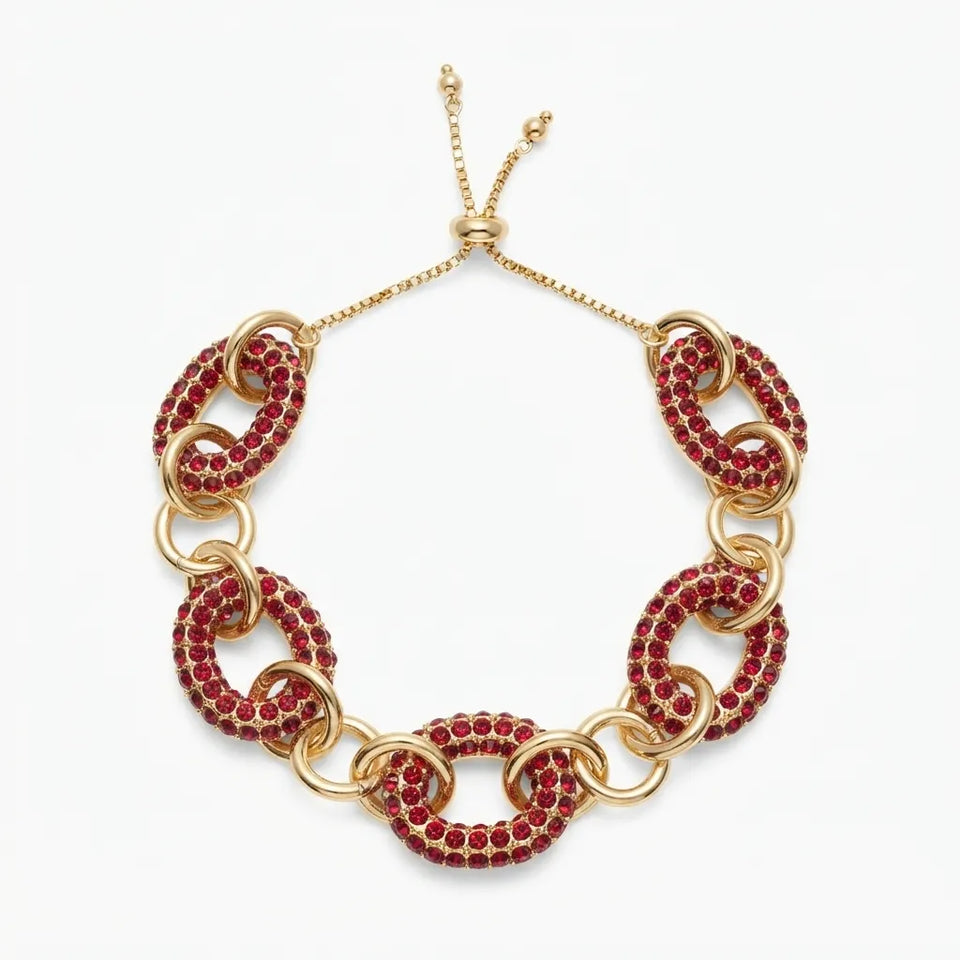 A gold chain link choker necklace embellished with rows of deep red rhinestones, displayed on a clean white background.