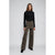 A woman modeling a black long-sleeve mock neck top and brown leopard-print wide-leg trousers against a light gray studio background.