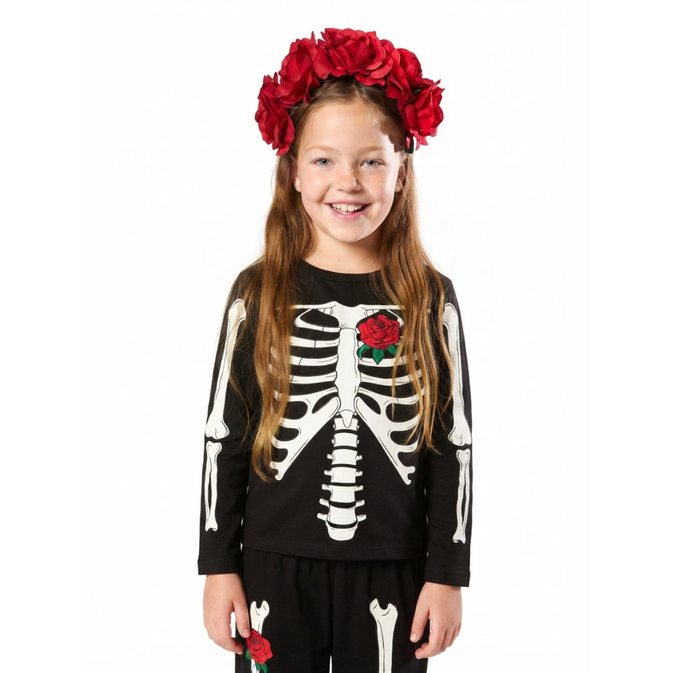 A young girl modeling a black skeleton-themed costume set, featuring a long-sleeve top with a white skeleton print and a red rose on the chest, matching black pants with white skeleton details, and a red flower crown headband.