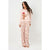 A woman modeling a two-piece pajama set consisting of a light pink long-sleeve top with a gingerbread man graphic and matching light pink wide-leg pants with a small floral print.