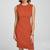 A woman wearing a sleeveless, knee-length orange-red sheath dress against a light gray studio background.