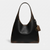 A Coach hobo shoulder bag in distressed black leather with brown undertones, featuring a small silver-tone Coach logo on the front and a hanging brown leather brand tag, set against a plain light gray background.