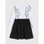 A girls' long-sleeve dress with a white upper bodice featuring black outline applique details, and a black flared skirt with small white polka dots, shown against a light gray background.