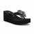 A black platform wedge sandal by Guess, featuring a thick black platform sole, a matching black wedge heel, and a black strap embellished with a large, detailed black and silver rhinestone flower.