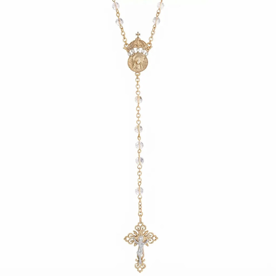 A gold-toned rosary necklace featuring clear faceted beads, a circular medallion with a crown and figure, and an ornate cross pendant, shown against a plain white background.