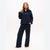 A woman modeling a matching navy blue fleece pajama set, consisting of a quarter-zip pullover and wide-leg pants, against a plain white studio background.