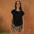 A woman modeling a black short-sleeve top and a beige-and-black zebra-print mini skirt against a textured warm brown studio backdrop.