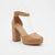 A tan platform high-heeled sandal with an ankle strap and clear plastic T-strap details, shown against a plain white background.