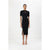 A model wearing a black short-sleeve ribbed midi dress with cutout details at the neckline and a thigh-high slit, paired with beige high-heeled sandals, set against a plain white studio background.