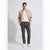 A man modeling a light beige bomber jacket over a white t-shirt, paired with olive green trousers and white sneakers, standing against a light gray studio background.