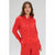 A woman modeling a bright red long-sleeve button-up shirt and matching red pants against a light gray studio background.