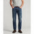 A man wearing a pair of medium-wash blue jeans with a light gray t-shirt and brown suede boots, standing against a light gray studio background.