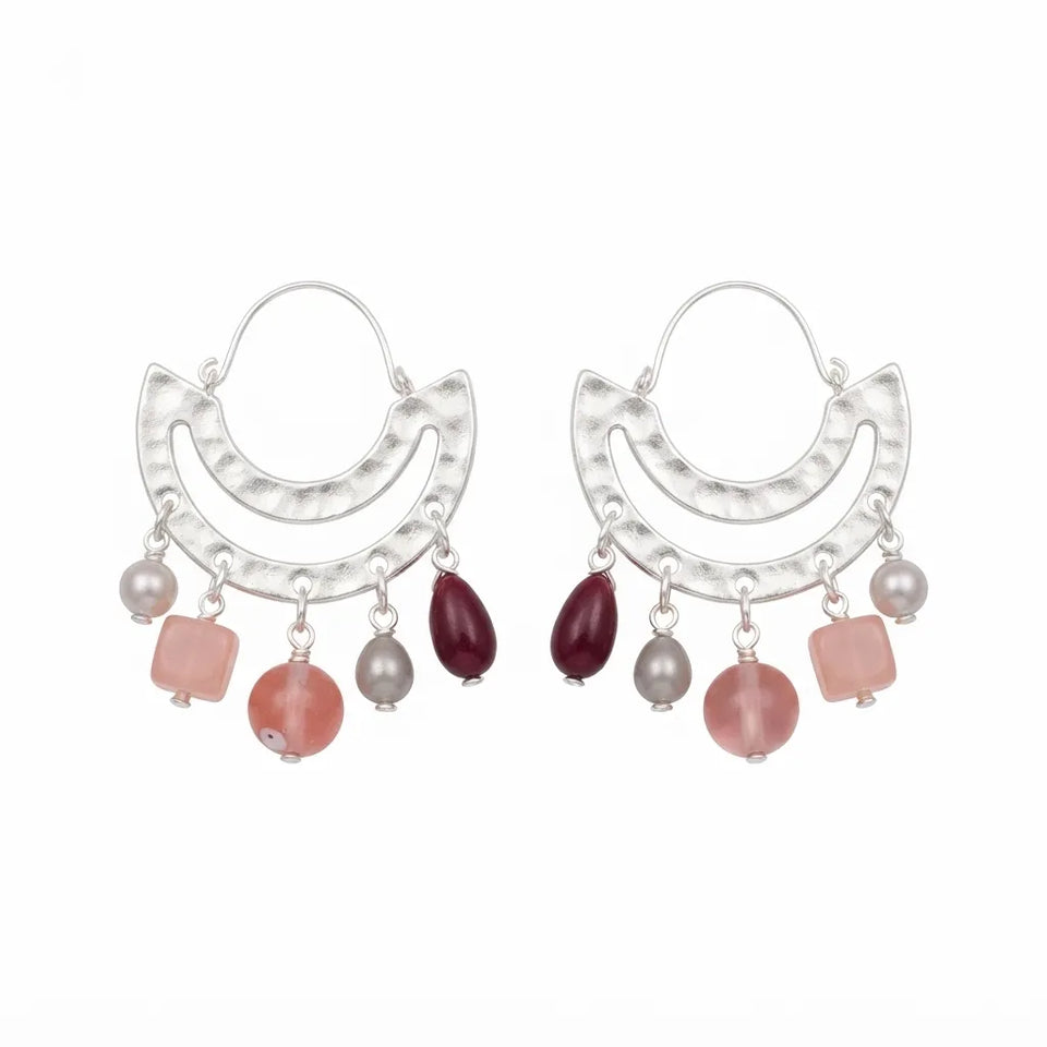A pair of silver crescent-shaped hoop earrings with dangling charms, including pink square beads, round pink beads, gray pearl-like beads, and a dark burgundy teardrop bead, shown on a plain white background.