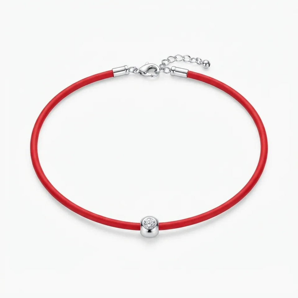 A red leather bracelet with a silver ball charm set with a clear crystal, shown on a light gray background.