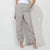 A model wearing light gray wide-leg jogger pants with an elastic waistband and drawstring ankle cuffs, paired with white strappy high-heeled sandals against a white studio background.
