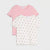 Two short-sleeve baby t-shirts by Baby Bell, one in solid light pink and the other in off-white with black polka dots, both featuring ruffled edges on the sleeves, displayed against a light gray background.