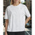 A woman wearing a white short-sleeve crewneck T-shirt with small silver rhinestone embellishments, photographed outdoors on a city street.