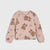 A children's long-sleeve crewneck sweatshirt in a dusty pink color, featuring an all-over print of teddy bears wearing winter hats and scarves, along with bow motifs, laid flat against a light gray background.