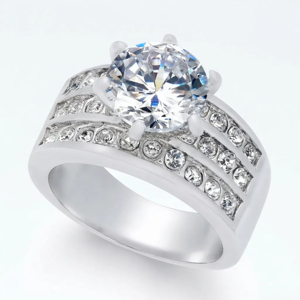 A silver-tone ring featuring a large round-cut clear center stone and rows of smaller clear stones along the split band, shown on a clean white background.