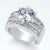 A silver-tone ring featuring a large round-cut clear center stone and rows of smaller clear stones along the split band, shown on a clean white background.